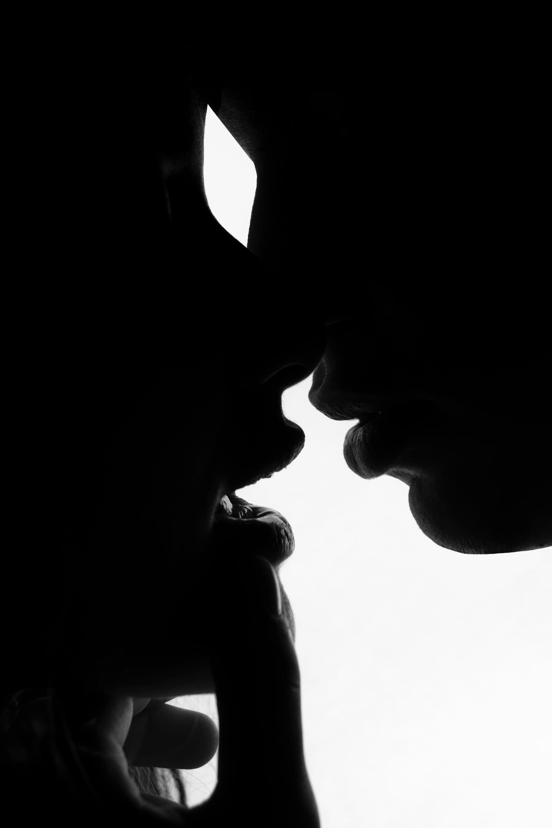 An intimate black-and-white silhouette of a couple about to kiss
